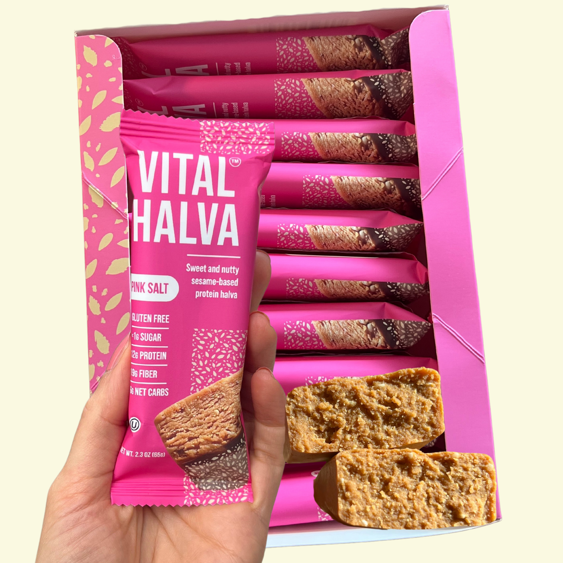 Box of Vital Halva Pink Salt with a hand holding one package against a light yellow background